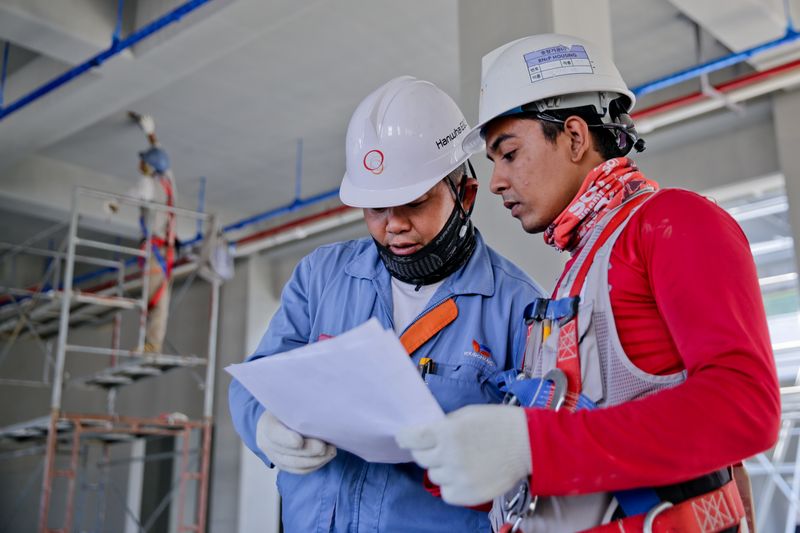 Two engineers in hard hats reviewing project documents on site